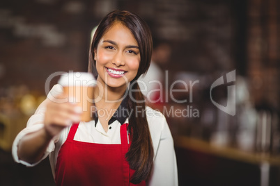 Smiling waitress handing a take-away mug