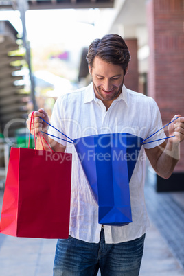 A happy smiling man looking into his shopping bags