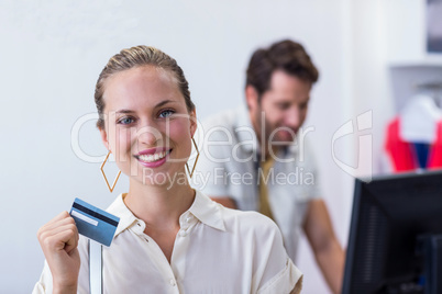 Smiling woman showing credit card to camera