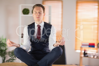 Calm businessman meditating in lotus pose