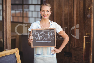 Smiling waitress showing chalkboard with open sign