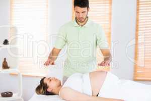 Relaxed pregnant woman getting reiki treatment