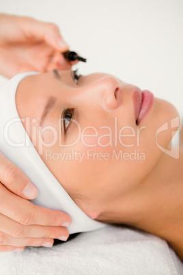 Hand applying mascara to beautiful woman