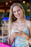 Smiling woman with shopping bags using smartphone