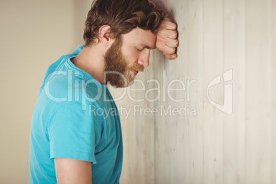 Troubled hipster leaning against wall