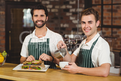 Two smiling baristas working together