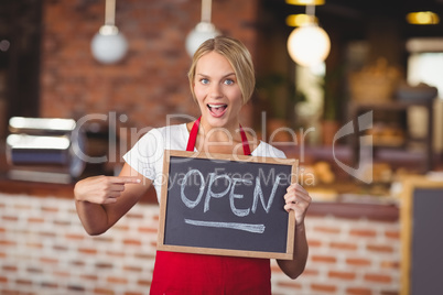 Pretty waitress pointing the chalkboard open sign