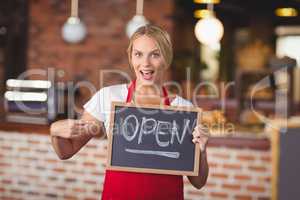 Pretty waitress pointing the chalkboard open sign
