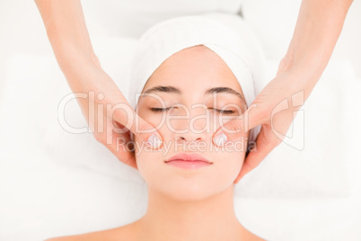 Attractive young woman receiving facial massage at spa center