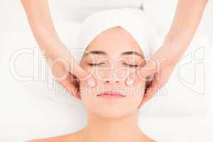 Attractive young woman receiving facial massage at spa center