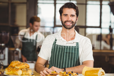 Smiling waiter tidying up the pastries