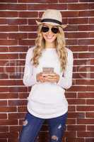Gorgeous blonde hipster with sunglasses using smartphone