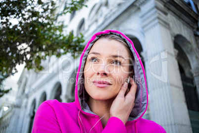 Portrait of a woman wearing a pink jacket putting her headphones