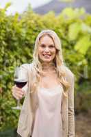 Young happy woman holding a glass of wine and looking at camera