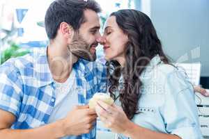 Couple kissing while holding cupcakes