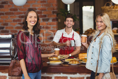 Smiling waiter and two customers looking at the camera