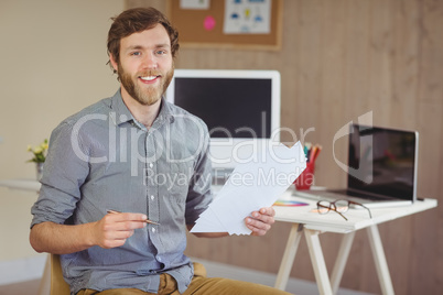 Bearded hipster smiling at camera holding notes