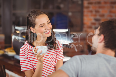 Smiling young woman enjoying coffee with a friend