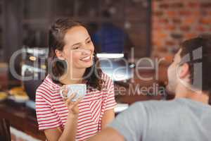 Smiling young woman enjoying coffee with a friend