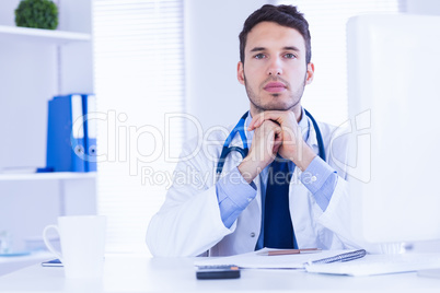 Portrait of doctor looking at camera with hands folded