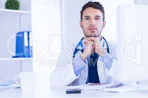 Portrait of doctor looking at camera with hands folded