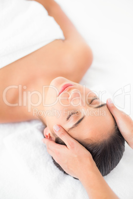 Attractive young woman receiving head massage at spa center