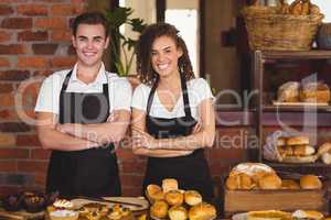 Smiling waiter and waitress with arms crossed