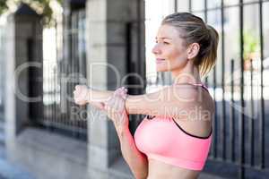 A beautiful woman stretching her arm against a fence