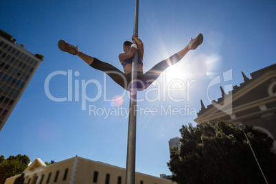 Athletic woman doing gymnastics on street sign