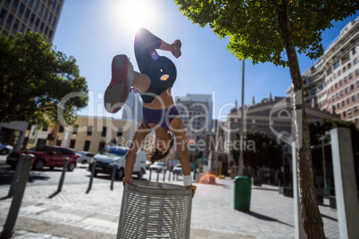Athletic woman performing handstand on bin