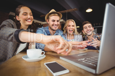 Laughing friends looking at laptop and pointing at screen