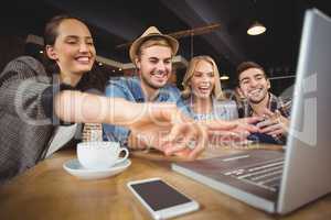 Laughing friends looking at laptop and pointing at screen
