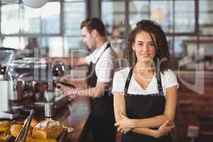 Smiling waitress with arms crossed in front of colleague