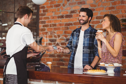 Smiling hipster giving credit card to barista