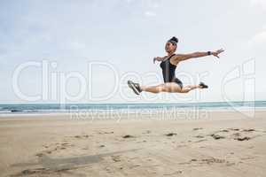 Fit woman leaping on the sand