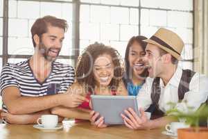 Happy friends laughing while looking at tablet