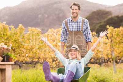 Happy couple in dungarees pushing a wheelbarrow