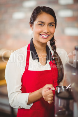 Smiling barista steaming milk at the coffee machine