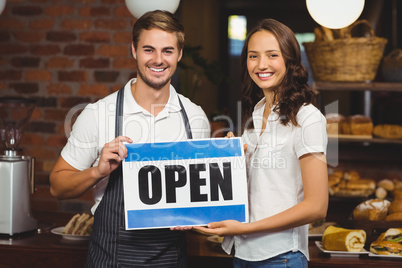 Smiling team posing with open sign