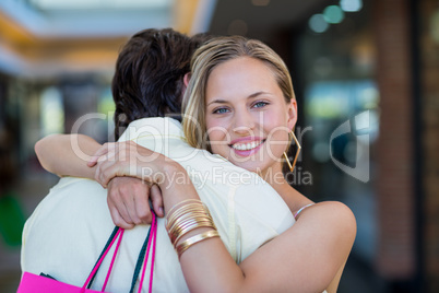 Smiling woman with shopping bags hugging her boyfriend