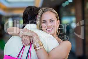 Smiling woman with shopping bags hugging her boyfriend