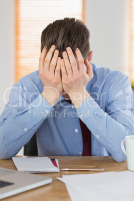 Stressed businessman with head in hands