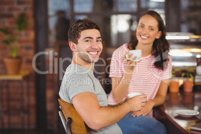 Smiling friends sitting and drinking coffee