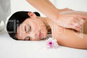 Pretty brunette enjoying a massage with flower