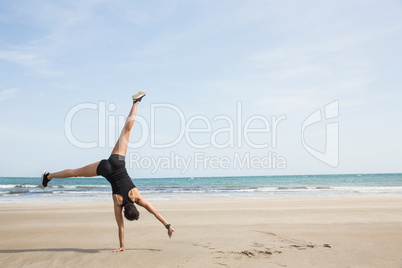 Fit woman cartwheeling on the sand