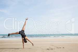 Fit woman cartwheeling on the sand