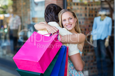 Smiling woman with shopping bags hugging her boyfriend