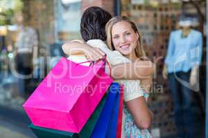 Smiling woman with shopping bags hugging her boyfriend