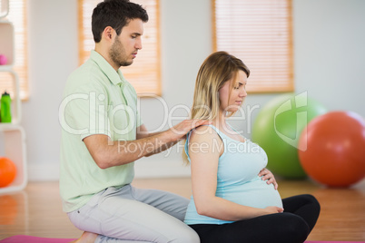 Masseur massaging shoulders of pregnant woman