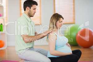 Masseur massaging shoulders of pregnant woman